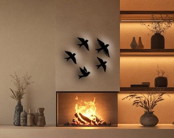 May include: A modern living room with a fireplace and decorative elements. The focal point is a fireplace with a glowing fire, above which are five black bird silhouettes. Shelves with vases and plants are illuminated by warm lighting.