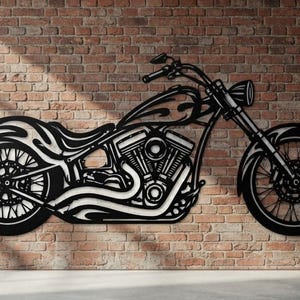 May include: A black metal wall art piece shaped like a custom chopper motorcycle. The design features intricate cutouts depicting the engine, spoked wheels, handlebars, and flame-like patterns along the fuel tank and rear fender of the motorcycle.