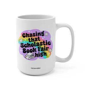 May include: White ceramic mug with a rainbow and cloud design. The text "Chasing that Scholastic Book Fair high" is printed on the mug.