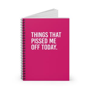 Puede incluir: Un cuaderno de espiral con una cubierta de color magenta vibrante que presenta el texto en blanco THINGS THAT PISSED ME OFF TODAY. El cuaderno tiene un lomo de espiral metálico negro en el lado izquierdo y está ligeramente abierto.
