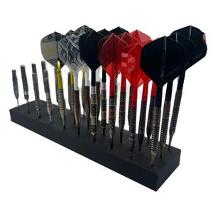 May include: A selection of darts in a black foam holder. The darts feature a variety of designs, including black, red, and silver. The flights display different patterns. The darts are arranged in a row, showcasing their diverse styles.