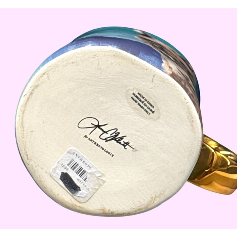 May include: A white ceramic mug with a black handle and the text "But First, Coffee" in a black, handwritten-style font. The mug is on a white surface.