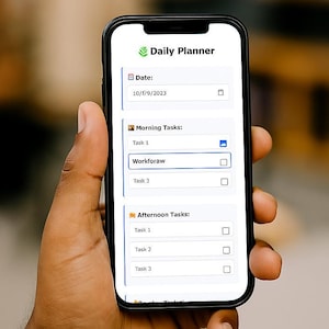 May include: A smartphone displaying a "Daily Planner" app interface. The screen shows a date, 10/1/9/2023, and task lists for morning and afternoon. The phone is held in a hand, with a blurred background.