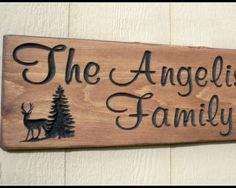 Personalized carved wood sign with family last name accented with deer and pine trees