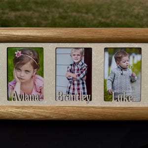 May include: A wooden triple photo frame with three individual openings. Each opening contains a photograph of a child. The names "Aviana", "Brantley", and "Luke" are cut out below each photo. The frame is made of light brown wood.