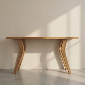 Op de afbeelding: Een lichtbruine houten consoletafel met een rechthoekig blad en gebogen poten. De tafel is gemaakt van lichtgekleurd hout en heeft een modern design. De gebogen poten geven een unieke uitstraling. De tafel is ongeveer 152 cm lang.