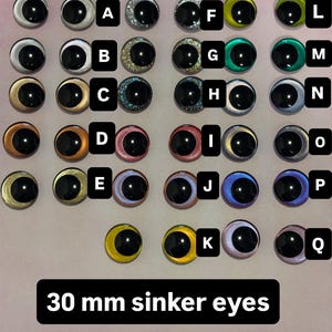 以下が含まれることがあります： 様々な色と仕上げの20個の人形用アイのコレクション。各アイには黒い瞳孔があります。目はAからQまでラベル付けされており、サイズは30mmです。目は光沢のある仕上げで、行に配置されています。
