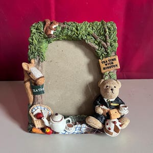 May include: A rectangular picture frame featuring a sculpted tree border with a squirrel, a horse head, and a teddy bear wearing a suit. The frame includes a sign reading TEA TIME WITH RINGTON, a teapot, a picnic basket, and a slice of cake.