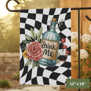 Peut inclure: Un drapeau de jardin avec un motif à carreaux noir et blanc. Il présente une bouteille bleue avec un bouchon et le texte "Drink Me". Une rose rose et d'autres fleurs entourent la bouteille. Le drapeau mesure 30.5 cm x 45.7 cm.