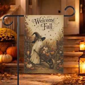 May include: A rectangular garden flag featuring a ghost wearing a witch hat and pushing a wooden wheelbarrow filled with pumpkins and autumn flowers. The text Welcome Fall is printed in a decorative script at the top. The scene is set in a rustic outdoor environment with fallen leaves and a lantern.