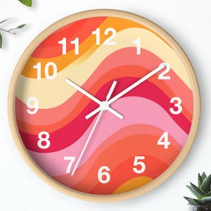 May include: Round wall clock with a wooden frame. The clock face features a retro design with wavy stripes in shades of orange, pink, and red. White numerals and hands provide a clear contrast against the colorful background. A decorative piece for any room.