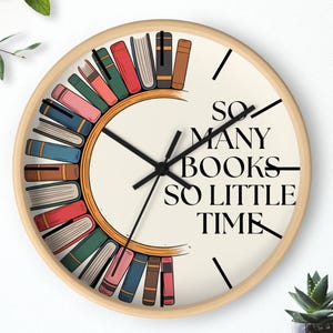 May include: A circular wall clock with a light wood frame. The cream-coloured clock face features black hands and the text "SO MANY BOOKS SO LITTLE TIME." A semi-circle of colourful books encircles the centre.