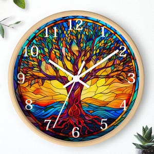 May include: Round wall clock with a stained glass design of a tree of life. The clock has a light wood frame, white hands, and white numerals. The tree design features red, orange, yellow, blue, and green colours.
