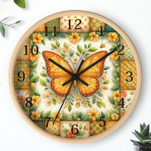May include: A round wall clock with a light wood frame. The clock face features a large orange butterfly in the center, surrounded by floral and geometric patterns in shades of yellow, green, and orange. Black clock hands indicate the time.