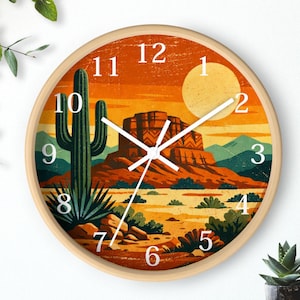 May include: Round wall clock with a desert landscape design. The clock face features a cactus, mesa, and sun in shades of orange, yellow, and green. The clock has a light wood frame and white clock hands and numbers.