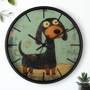 Könnte beinhalten: Eine runde Wanduhr mit schwarzem Rahmen. Das Zifferblatt zeigt eine skurrile Illustration eines Dackelhundes in Schwarz, Braun und Orange vor einem strukturierten tealfarbenen Hintergrund. Schwarze Zeiger zeigen die Uhrzeit an.
