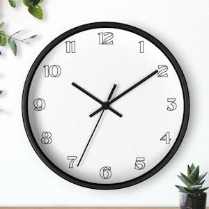 May include: A round wall clock with a black frame and a white face. The clock features black hour, minute, and second hands. The numbers one through twelve are printed in a black outline font around the perimeter of the white clock face.