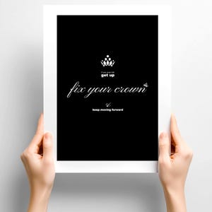 Può includere: Una stampa in bianco e nero con le parole "If you ever fall, get up, fix your crown, keep moving forward." Una grafica a corona bianca è sopra le parole "get up." La stampa è tenuta da due mani.