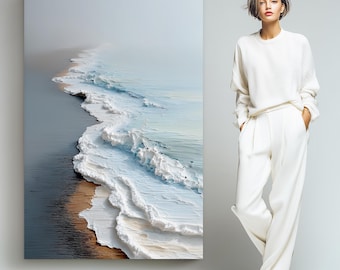 Peut inclure: Une impression murale rectangulaire de 101,6 cm sur 152,4 cm, représentant une vue aérienne de vagues océaniques s'écrasant sur une plage de sable avec un horizon brumeux. À côté de l'impression se tient une personne portant un pull blanc.