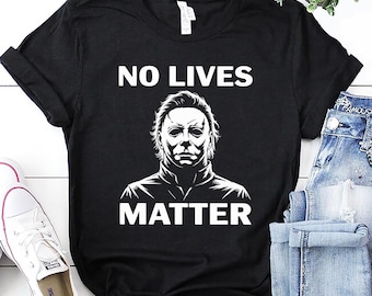 May include: Black t-shirt featuring the text "NO LIVES MATTER" above a white graphic of a character's face. The shirt is shown with blue jeans and white trainers.