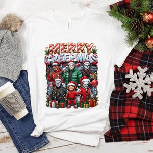 Puede incluir: Camiseta blanca con un gr&aacute;fico colorido que dice "MERRY CREEPMAS" con personajes de pel&iacute;culas de terror con gorros de Pap&aacute; Noel. El dise&ntilde;o incluye bastones de caramelo y regalos. La camiseta se muestra con un gorro gris, jeans y una bufanda a cuadros roja y negra.