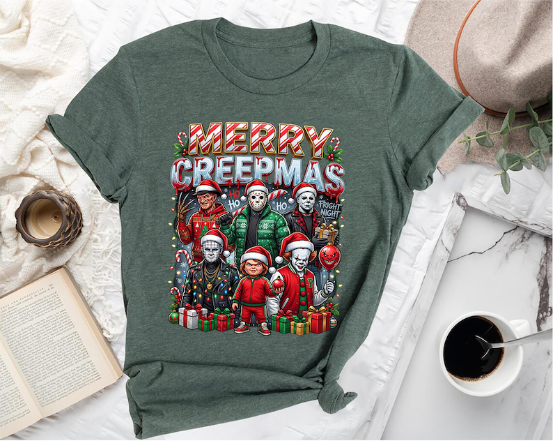 Puede incluir: Camiseta verde con un gr&aacute;fico que presenta personajes de pel&iacute;culas de terror con gorros de Pap&aacute; Noel y el texto "MERRY CREEPMAS". El dise&ntilde;o incluye bastones de caramelo y regalos envueltos, creando un tema festivo pero espeluznante.