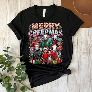 Puede incluir: Camiseta negra con la frase "MERRY CREEPMAS" y dibujos de personajes de pel&iacute;culas de terror con gorros de Pap&aacute; Noel. El dise&ntilde;o incluye luces navide&ntilde;as y regalos, creando un tema festivo y espeluznante.
