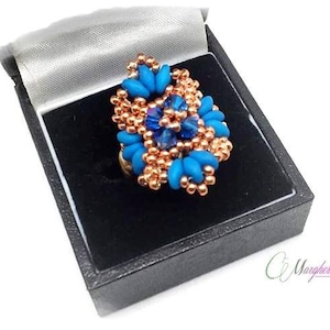 May include: A blue and copper beaded ring with a crystal centre, displayed in a black velvet ring box.