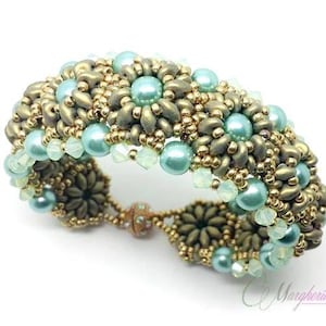 Può includere: Un braccialetto di perline dorate e turchesi con un design floreale. Il braccialetto è realizzato con perline piccole e ha una chiusura a scatto.