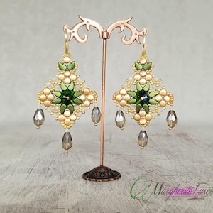 May include: Gold and green beaded earrings with a geometric design and dangling crystal drops. The earrings are displayed on a stand.