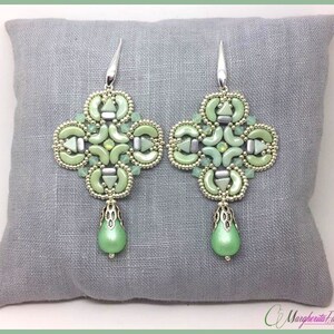 Op de afbeelding: Een paar groene en zilveren kralen oorbellen met een traanvormige hanger. De oorbellen zijn in een geometrisch patroon en hebben een delicate, vrouwelijke uitstraling.