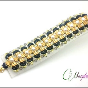 Peut inclure: Un bracelet de perles avec un motif de perles dorées, noires et nacrées. Le bracelet a un fermoir doré et est présenté sur une surface blanche. Le design comprend de petites perles transparentes et le texte "Margherita Fusco design".