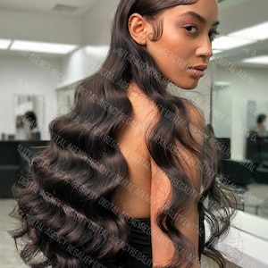 Può includere: Una donna con lunghi capelli ondulati castano scuro acconciati con una riga laterale. I capelli scendono sulla schiena e sulla spalla. La donna guarda sopra la spalla verso la fotocamera. Lo sfondo è un interno sfocato.