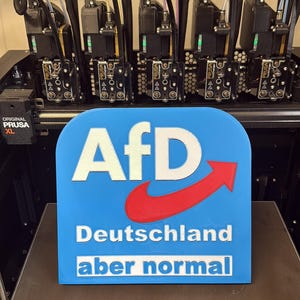 Könnte beinhalten: Ein blaues und rotes 3D-gedrucktes Schild mit dem Text "AfD Deutschland aber normal".