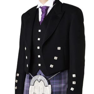Puede incluir: Chaqueta formal negra con botones cuadrados plateados, usada sobre un chaleco a juego. El atuendo incluye una corbata morada, una camisa blanca y un kilt escocés tradicional a cuadros morados y azules. Un sporran blanco con detalles plateados completa el conjunto.