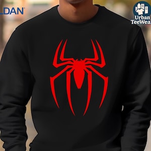May include: Black sweatshirt with a large red spider logo on the front. The spider logo is a stylized design with long, curved legs and a central body. The sweatshirt has a crew neck and long sleeves. The brand name 'GILDAN' is printed on the upper left side.