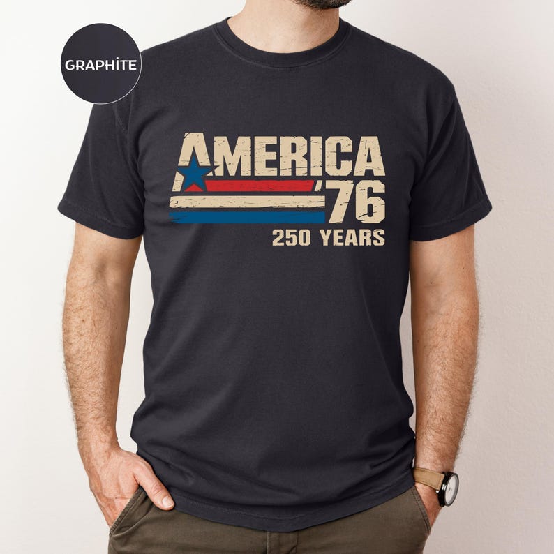 May include: Dark grey t-shirt featuring the text "AMERICA '76 250 YEARS" in a retro design. The graphic includes a blue star, red and blue stripes, and distressed lettering, commemorating the nation's anniversary.