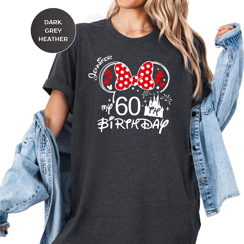 Puede incluir: Camiseta gris oscuro jaspeado con un dise&ntilde;o de Minnie Mouse para un 60 cumplea&ntilde;os. El dise&ntilde;o incluye un lazo rojo con lunares blancos, el nombre "Jennifer", el n&uacute;mero "60" y las palabras "my birthday".