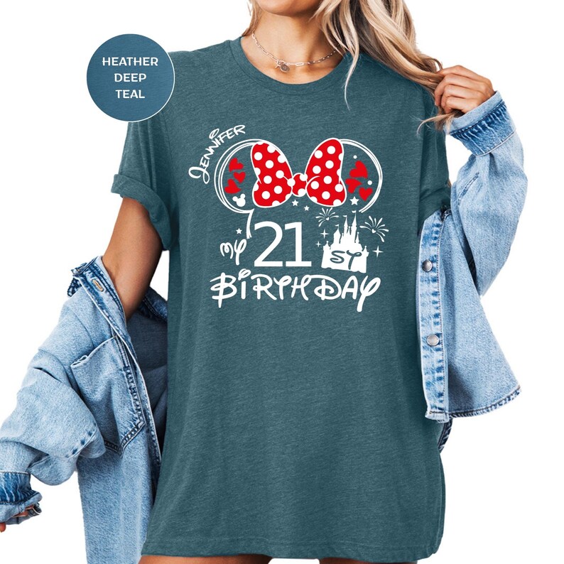 May include: Heather deep teal t-shirt with a white graphic. The graphic includes a red polka dot bow, the name "Jennifer", the number "21", and the words "My Birthday". The shirt has rolled-up sleeves.
