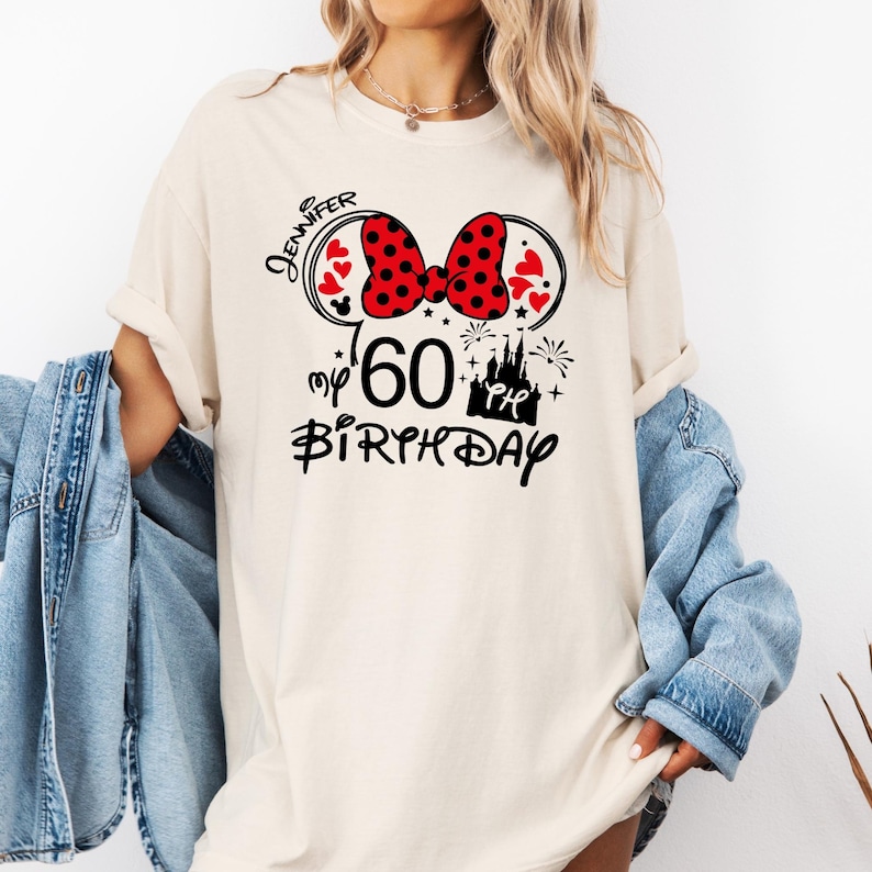 Puede incluir: Camiseta color crema con un dise&ntilde;o inspirado en Minnie Mouse para un 60 cumplea&ntilde;os. El dise&ntilde;o incluye un lazo rojo de lunares, corazones, el nombre "Jennifer", un castillo y las palabras "my 60th Birthday" en escritura negra.