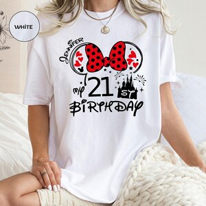 May include: White t-shirt with a Minnie Mouse-themed design for a 21st birthday. The design includes a red polka dot bow, hearts, the name "Jennifer", a castle, fireworks, and the words "my 21st Birthday".