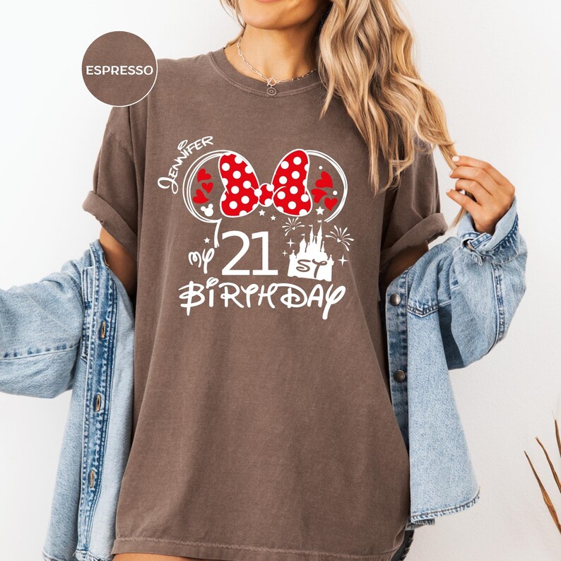 May include: Espresso-colored t-shirt with a white graphic design. The design includes a red and white polka-dot bow, the name "Jennifer", the number "21", a castle, and the words "my birthday".