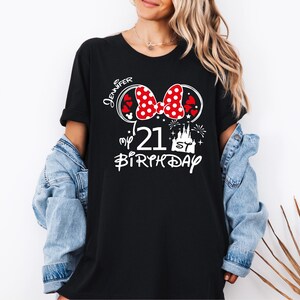 May include: Black t-shirt with a Minnie Mouse-themed design. The design includes a red polka dot bow, the number "21", a castle, and the word "Birthday". The name "Jennifer" is also printed on the shirt.