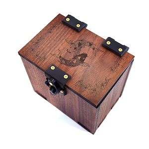 Peut inclure: Une boîte en bois brun foncé avec un motif gravé de deux carpes koï et des motifs floraux sur le couvercle. Des fermoirs et des charnières en métal noir sécurisent la boîte, idéale pour ranger de petits objets.