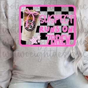 Op de afbeelding: Een grijze sweatshirt met een roze en zwart geruit ontwerp. Het ontwerp bevat een koffiedrank en de tekst "SUSPECT RUNS ON 7BREW". Een roze ster is ook in het ontwerp opgenomen.