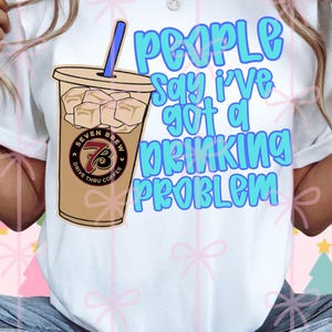 May include: White t-shirt with a graphic of an iced coffee and the text "People say I've got a drinking problem" in blue bubble letters. The coffee cup has the "Seven Brew Drive Thru Coffee" logo.