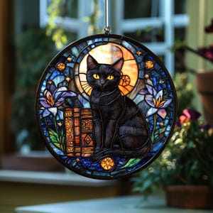 Pode incluir: Uma janela redonda de vitral com um gato preto de olhos amarelos, sentado em frente a uma pilha de livros. A janela tem um esquema de cores azul, laranja e amarelo com elementos florais e celestiais.