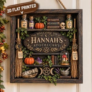 Op de afbeelding: Een rechthoekige houten wanddisplay met de tekst 'Welcome to Hannah's Apothecary'. Het bevat miniatuur glazen flesjes, pompoenen, boeken, een schedel, een stolp met paddenstoelen, bezems, kristallen, een vijzel met stamper en pentagramsymbolen.