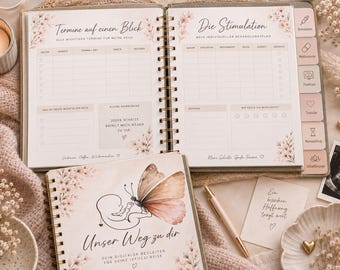 May include: A spiral-bound planner titled Unser Weg zu dir with a butterfly and baby illustration on the cover. The open pages feature German text including Termine auf einen Blick and Die Stimulation, with tables for tracking medical appointments, medication, and daily notes, decorated with soft pink floral accents.
