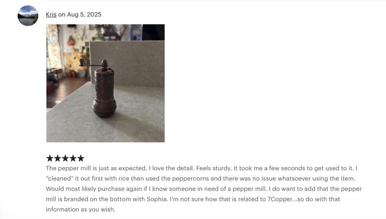May include: A cylindrical copper pepper mill featuring an intricate embossed pattern across its body, a rounded base, and a small manual crank handle at the top for grinding. The metal surface displays a dark, weathered finish with visible texture.